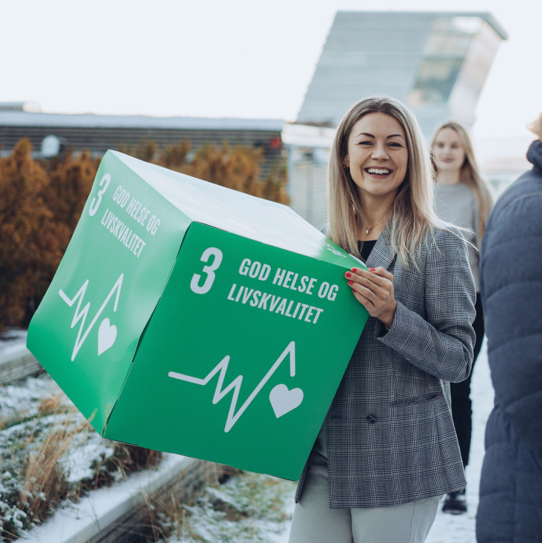 Smiling woman holding box with sustainability goals
